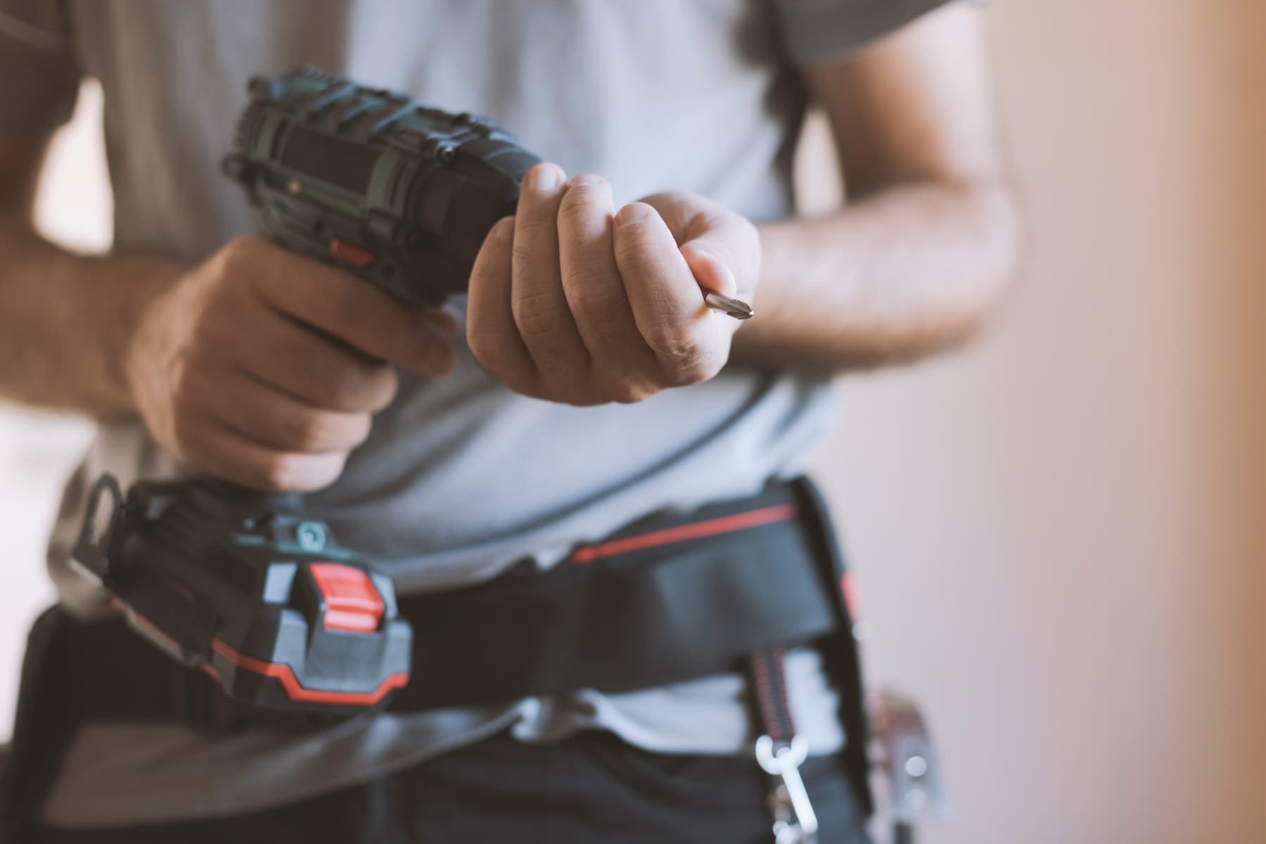 Carpenter with a cordless drill and a loaded tool belt