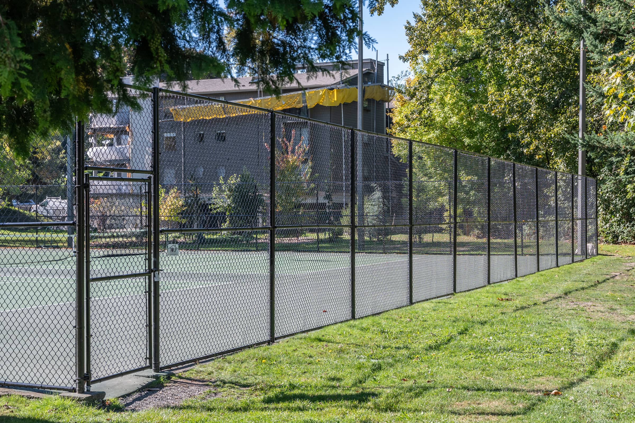 Black chain-link fence and gate around a park tennis court
