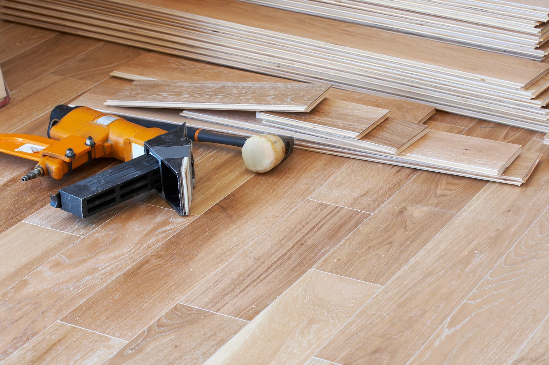 Plank flooring mid-install with tools and boards