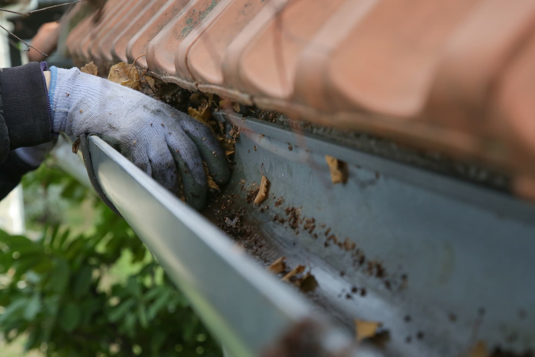 Scooping packed debris out of a roof gutter