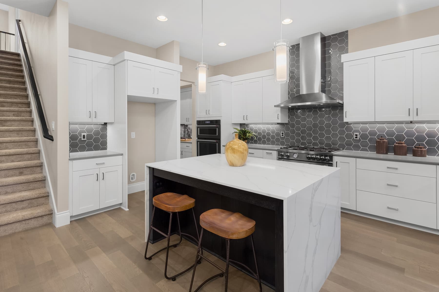 Remodeled kitchen with white cabinets, quartz island and stools