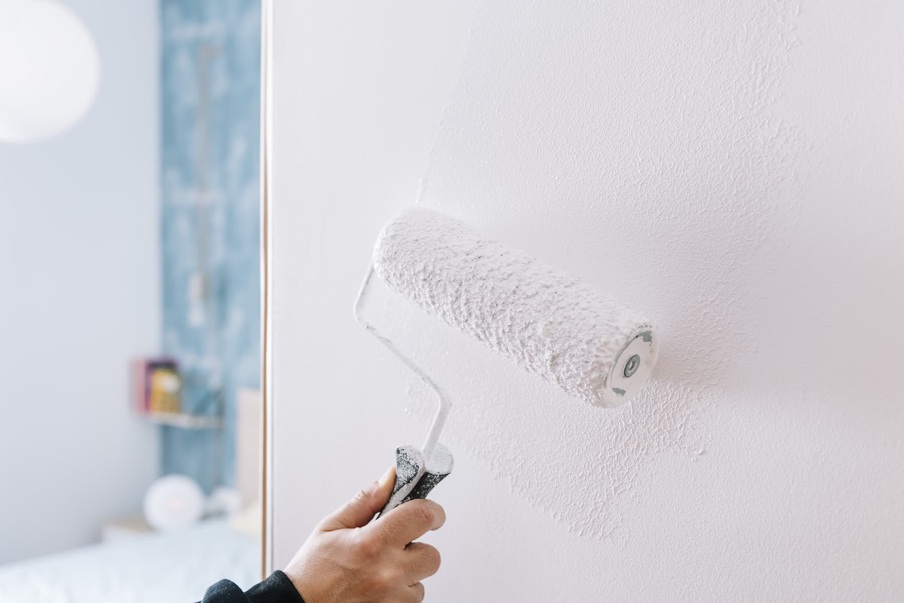 Roller painting an interior wall white