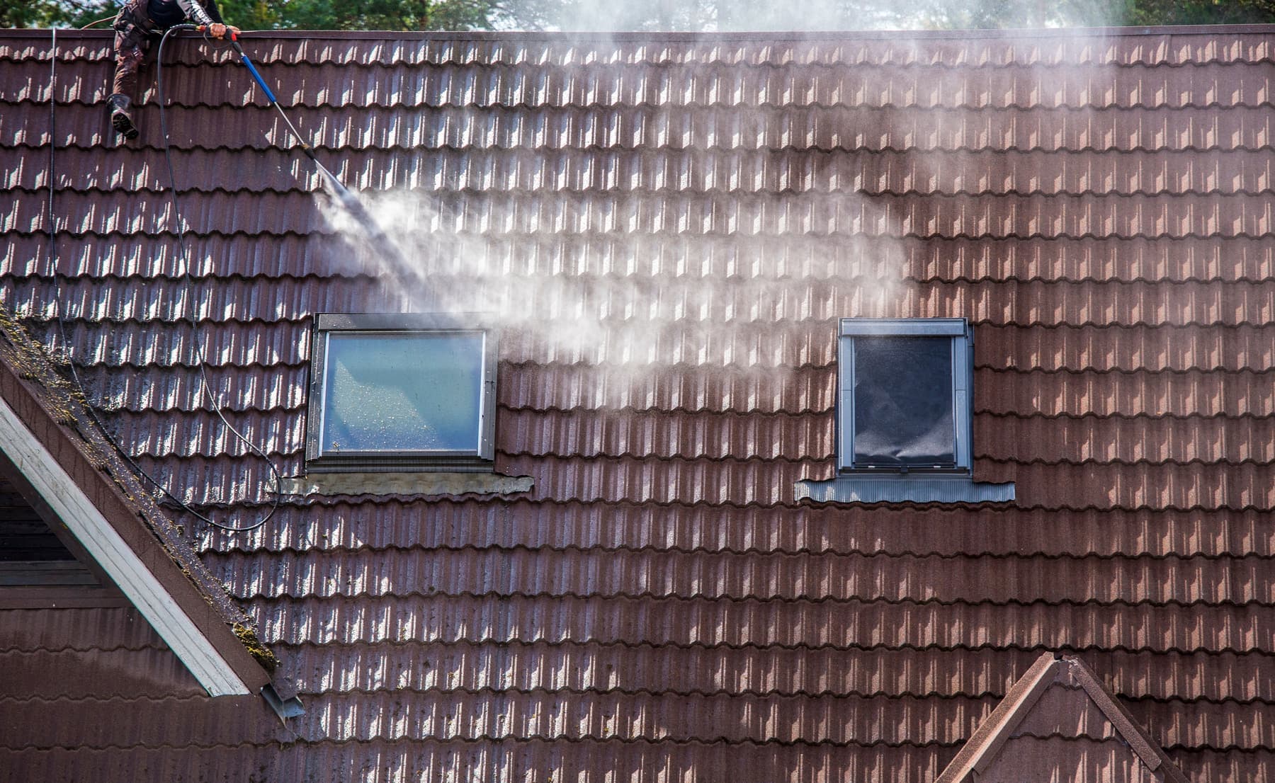 Tile roof being cleaned, with skylights